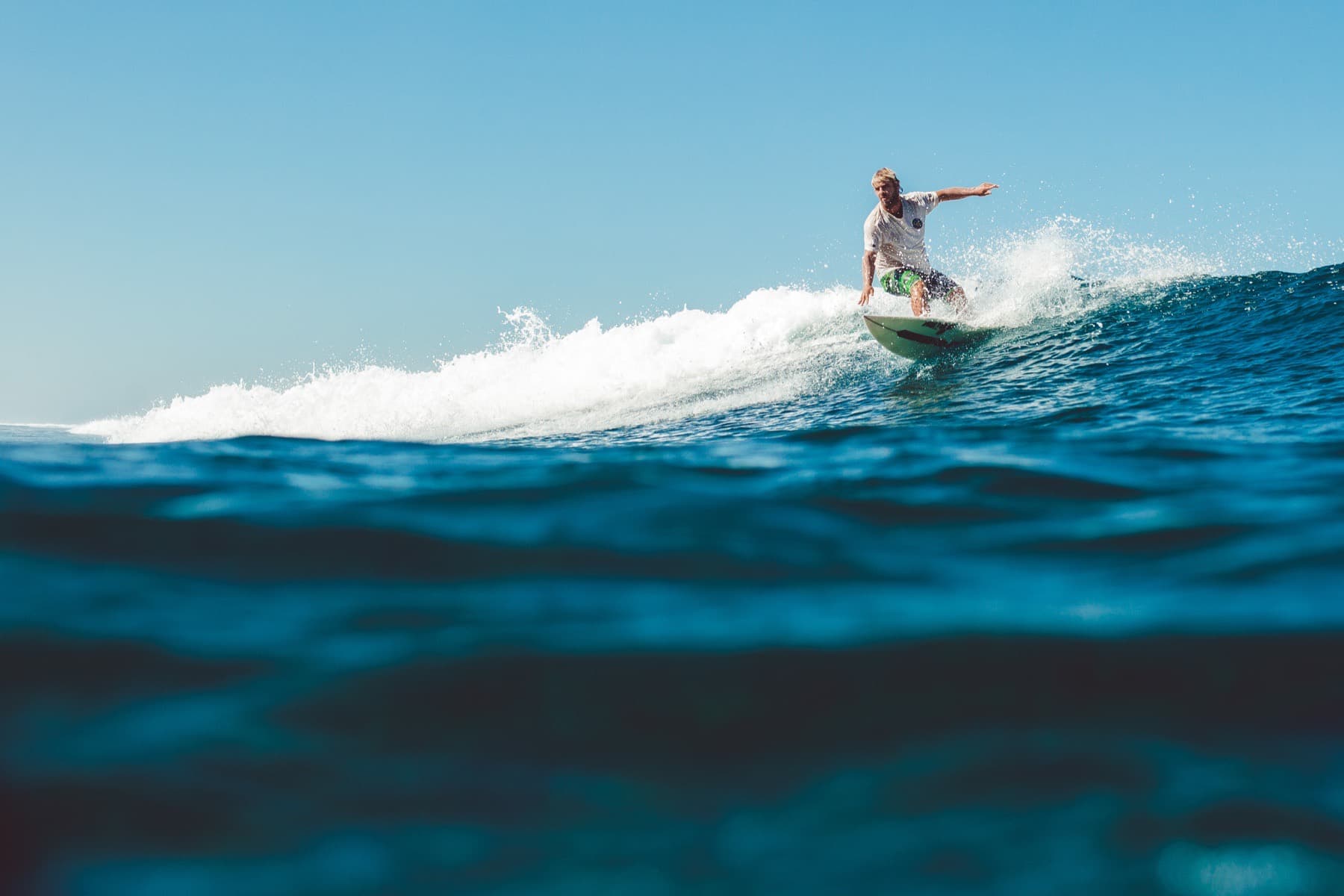 Surfer riding a small wave in clear blue water