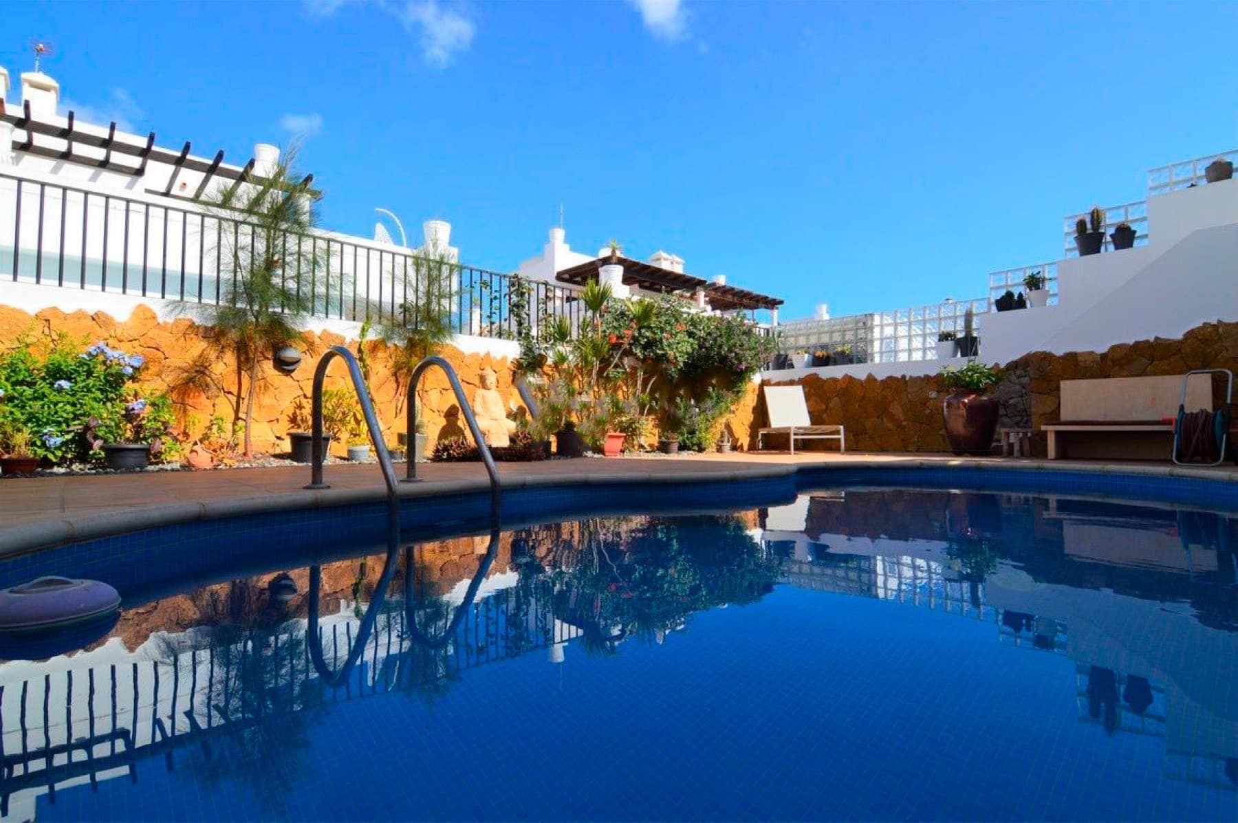 Pool and sunny terrace surrounded by white walls and plants at Coco Surfhouse